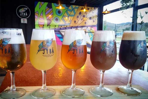 Cervejas de diferentes estilos colocadas em copos lado a lado para mostrar os diferentes níveis de formação de espuma da cerveja