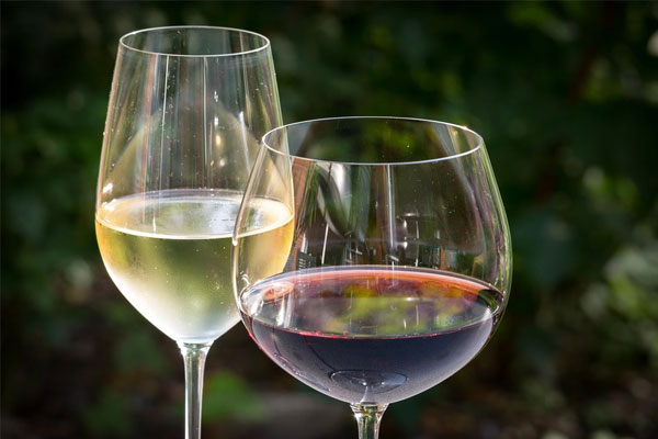 Duas taças de vinho, uma com vinho branco e outra com vinho tinto