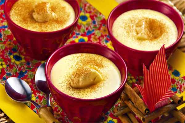 Potinhos com curau de milho verde em uma mesa de doces de festa junina