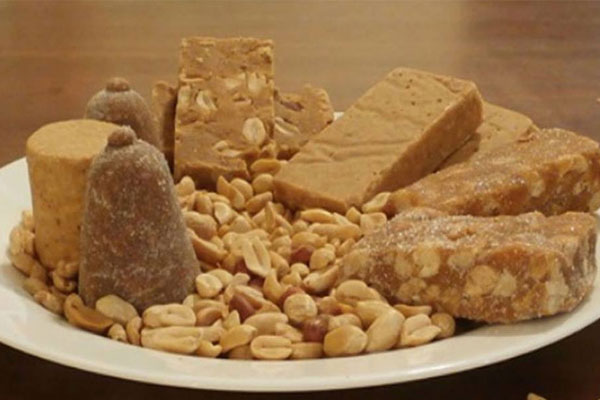 Vários doces de amendoim dispostos em uma mesa. Na foto tem cajuzinho, amendoim natural, pé de moleque, paçoca e pé de moça