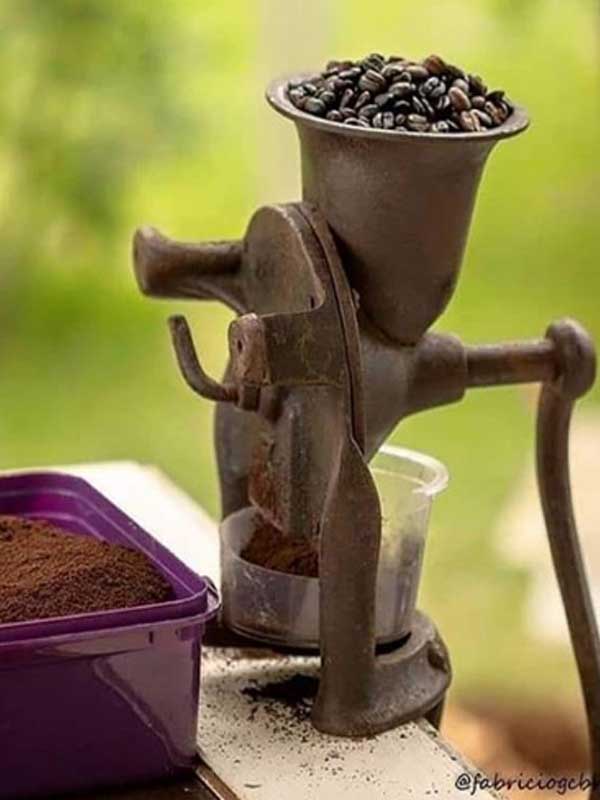 Grãos de café com chocolate no moedor e ao lado um pote cheio do pó já moído