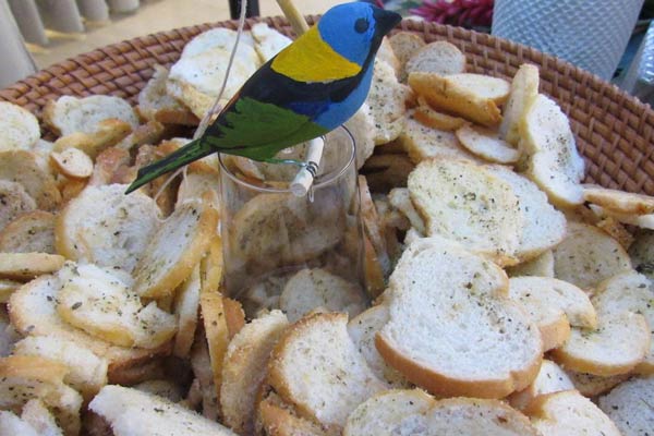 Bandeja com torradas e decorada com um passarinho de madeira Saíra Sete Cores