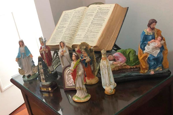 Imagem de mesa de centro com bíblia e várias imagens de santos de resina